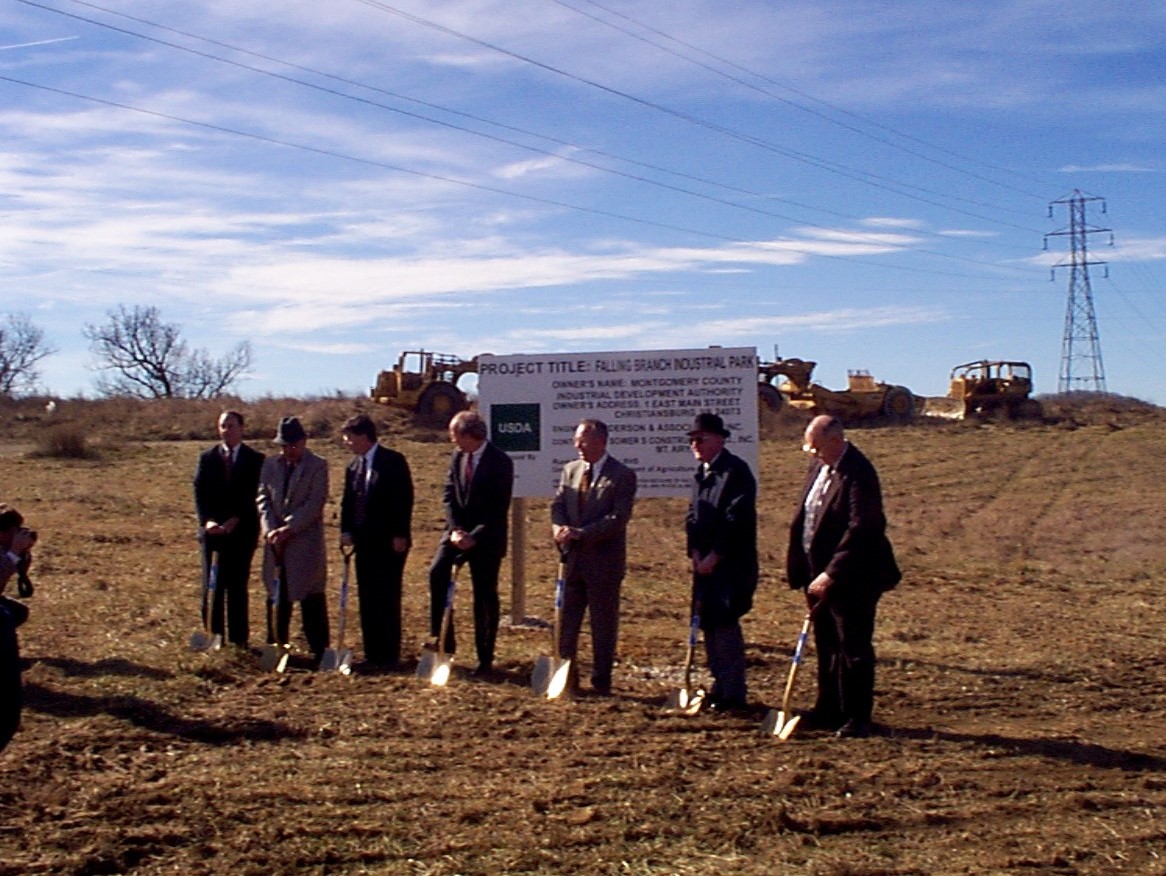 Seven men stand with shovels in the dirt at the site of future Falling Branch Corporate Park for the groundbreaking ceremony held in 1999